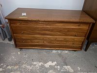 Full front view of the cedar chest showing three front panels with metal knobs and wood grain pattern.