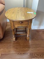 Front view of the wood end table showing the drawer, turned legs, and wood grain top surface.