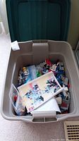 Overhead view of gray plastic bin containing loose LEGO elements and instruction manual.