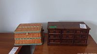 Photo of the woven sewing basket next to a wooden jewellery box with multiple drawers on a wooden surface