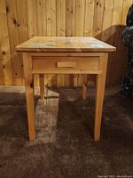 Front view of the pine wood side table showing drawer and legs