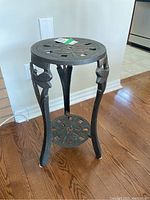 Full view of the metal table showing three legs with dragonfly accents and round lower shelf.