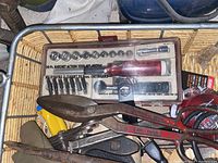 Close-up of basket with 20-piece socket set in plastic case, metal snips, files, and electrical cord.