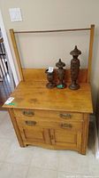 Front view of antique wood washstand with three wooden decorative pieces on top.