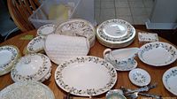 Wide view of the Wedgwood china set on wood table including plates, cups and saucers, large and small serving pieces, covered dishes, and a trinket box.