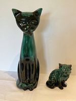 Photo showing large and small Blue Mountain Pottery cat figurines side by side, capturing size difference and glaze color.