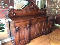 Full front view of the carved wood buffet showing removable top, paneled doors, and carved decorative backsplash