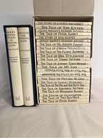 Two volumes of Lewis Carroll's Alice's Adventures in Wonderland and Through the Looking Glass in a blue slipcase alongside a boxed set of 23 Beatrix Potter Peter Rabbit books with white spines.
