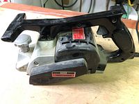 Left side view of the black and metallic silver Craftsman power planer showing ergonomic handle and trigger with ventilation slots and a red label.