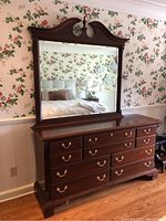 Full view of 10 drawer dresser with large mounted mirror, showing floral wallpaper background.