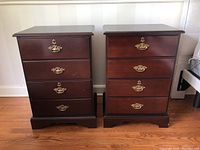 Pair of matching dark wood Bombay 2-drawer night stands side by side showing front view with brass handles and keyholes.