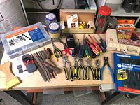Overview of the assorted tool lot laid out on a table showing files, pliers, screwdrivers, hardware boxes, stapler, and other accessories.