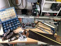 Full overview of hand tools on a table including hand planes, saws, hardware organizer, and accessories