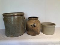 Front view of all three vintage stoneware pots showing varied sizes and glaze colors.
