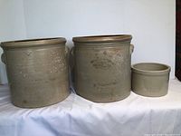 Front view of three Belleville Pottery crock pots arranged side by side showing sizes and surface wear