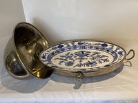 Metal warming dish base containing blue and white porcelain insert with Onion pattern, side handles visible.