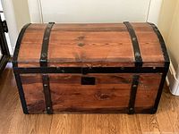 Front view showing pine wood construction with metal straps and lock plate.