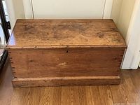 Front view of the vintage pine blanket box showing top and front surface with some spots and scratches.