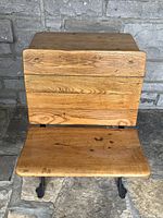 Front view of the vintage school desk showing closed wooden top and fold-out wooden seat with visible wear.