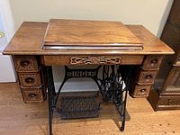 Front view of the vintage Singer wooden cabinet with treadle base and sewing machine compartment.