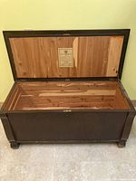 Open cedar-lined blanket chest showing natural wood interior and attached label certifying cedar wood and exterior finishes.