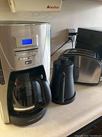 Sunbeam stainless steel two-slice toaster with black trim next to black electric kettle and Black & Decker coffee maker on counter.