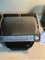Photo of T-fal OptiGrill closed lid with control panel featuring multiple cooking modes and colored indicator rings.