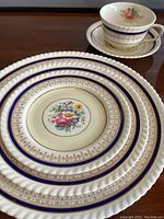 Stack of plates showing floral center design and blue and gold patterned rims.