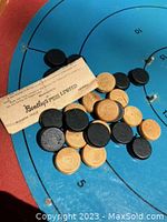 Close-up image showing black and natural wood checkers pieces resting on the game board alongside a folded instruction leaflet from Bentley Games Limited.