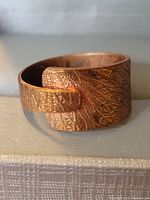 Photo of copper ring showing textured leaf-like embossed design and wrap-around style.