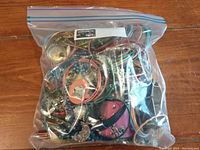 Photo of assorted costume jewelry inside a transparent zip-lock bag showing various bracelets, necklaces, and pendant pieces.