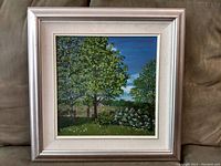 Front view of framed painting depicting a landscape with trees and sky, mounted in a white and silver frame with matting.