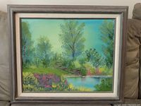 Full view of the framed landscape painting depicting trees, a pond, and colorful foliage with a distressed wooden frame.
