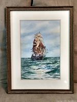 Framed watercolor painting of a sailing ship at sea, matted and behind glass in wood frame.