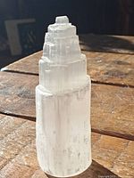 Front view of the translucent white selenite crystal tower on wooden surface.