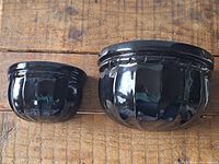 Top front view of two black ceramic wall planter sconces showing glossy finish and vertical fluted pattern.