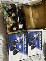 Three boxes mostly containing unopened garden lights with some adapters and stakes visible inside one box.