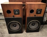Front view of pair of 3a Apogee speakers with visible woofers, tweeters and port holes in rosewood veneer cabinets.