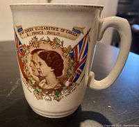 Front side of ceramic mug with colored portraits of Queen Elizabeth II and Prince Philip, and decorative maple leaves and flags.