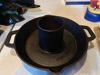 Side view of cast iron bundt pan showing central tube and two side handles.