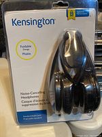 Front view of sealed Kensington noise-cancelling foldable headphones in original packaging.
