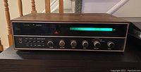 Front view of the Procom by Pointon stereo receiver showing the wood casing and illuminated tuning dial.