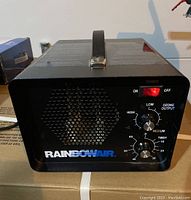 Front view showing power switch, ventilation grille, two control knobs for ozone output and timer, and RainbowAir branding.
