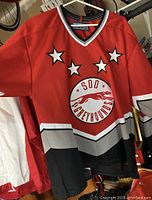 Red/black/white/grey Soo Greyhounds hockey jersey front view showing logo and star accents on chest.