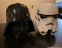 Front view of the two coin banks showing Darth Vader and Stormtrooper helmets.