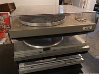 Top view of two vintage turntables stacked, visible dust covers and Akai label on front right.