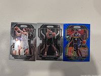Photo showing three basketball trading cards: Joe Harris and Kessler Edwards of the Brooklyn Nets, and Paul Millsap of the Denver Nuggets with a blue holographic Prism design.