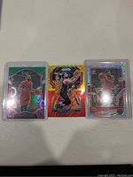 Three Fred VanVleet basketball cards laid out on a white surface: a Select card, a Donruss Optic card with a red-orange background, and a Donruss Optic Prism card in a protective case.