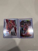 Two Kyle Lowry basketball cards in sleeves on a light surface with some glare on one card reflecting light.