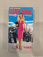Front cover of Legally Blonde VHS showing Reese Witherspoon in a red dress with background cast and dog, with title and tagline visible.